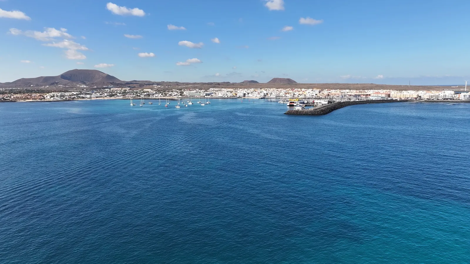Vista aérea de la bahía de Corralejo con su dársena, el casco urbano y los conos volcánicos del norte de Fuerteventura. Fotografía de Grupo Oby