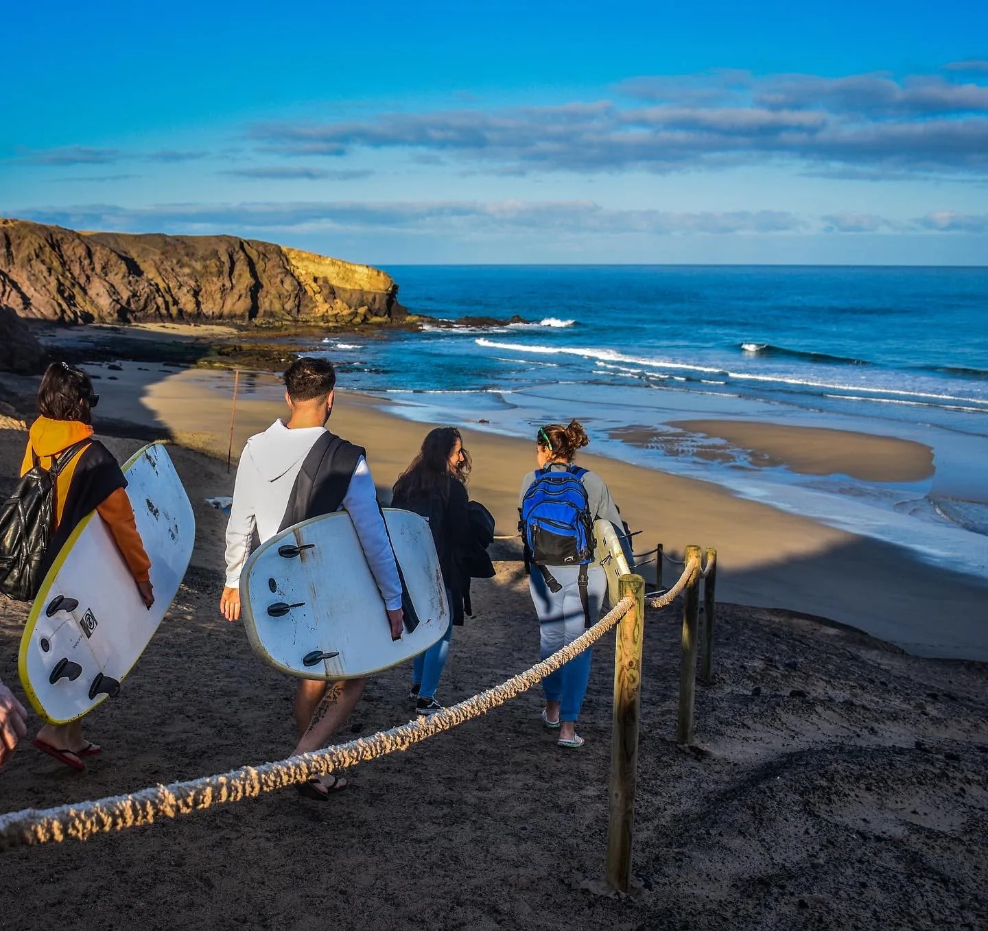 Groupe descendant vers une plage de sable du sud de Fuerteventura avec des planches de surf