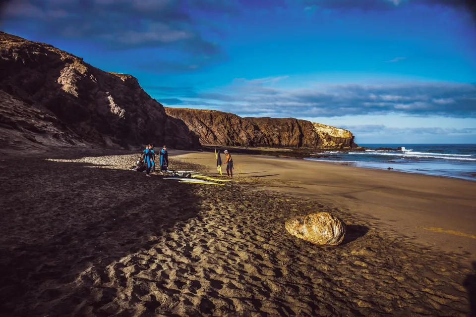 Surfistas y tablas en una playa junto a acantilados · Flow Surf Project
