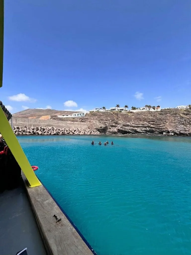 Vista desde el barco hacia la costa de Jandía y nadadores lejanos